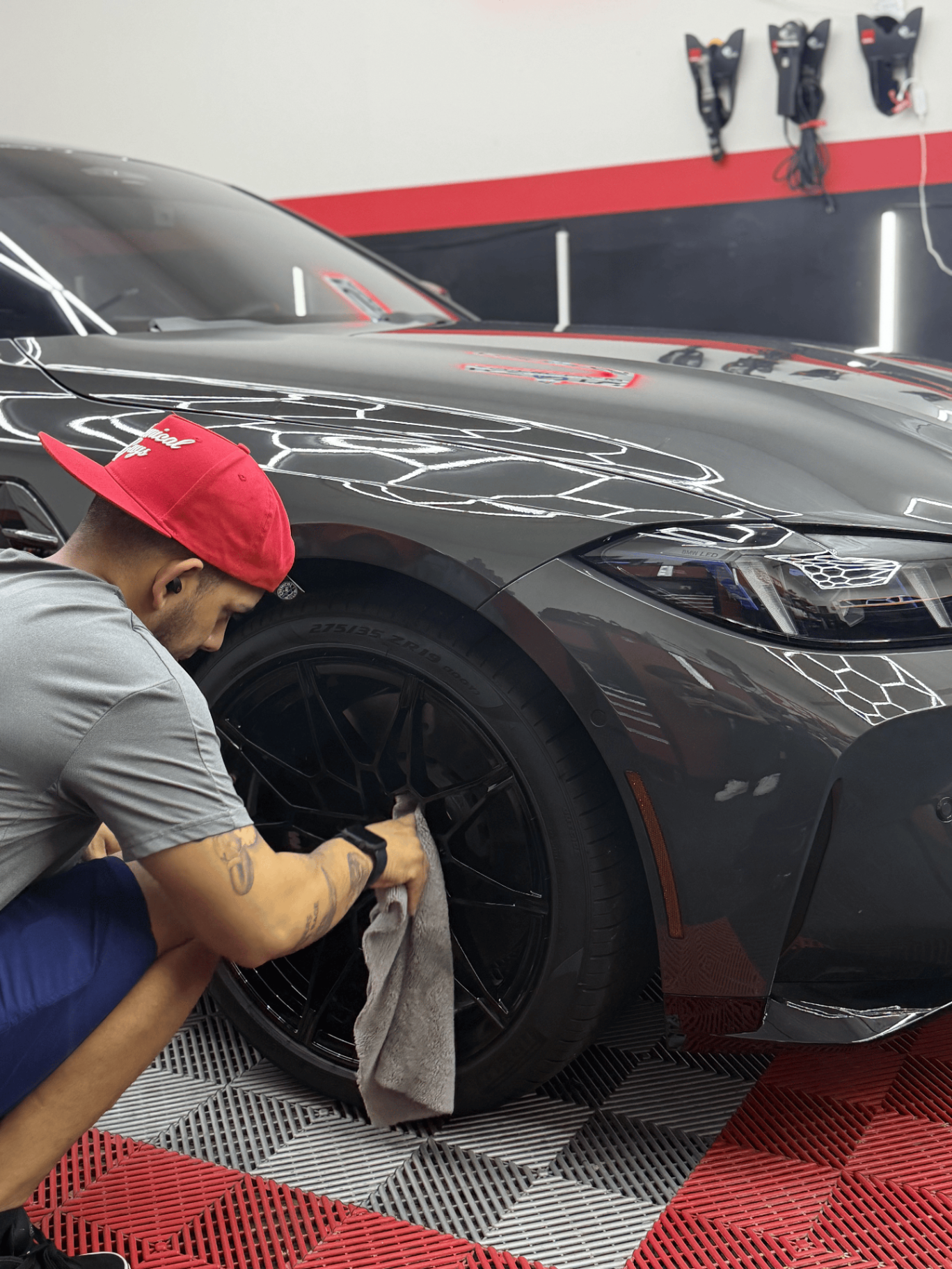ICON Auto Lab technician wiping down the wheel of a grey BMW after coating