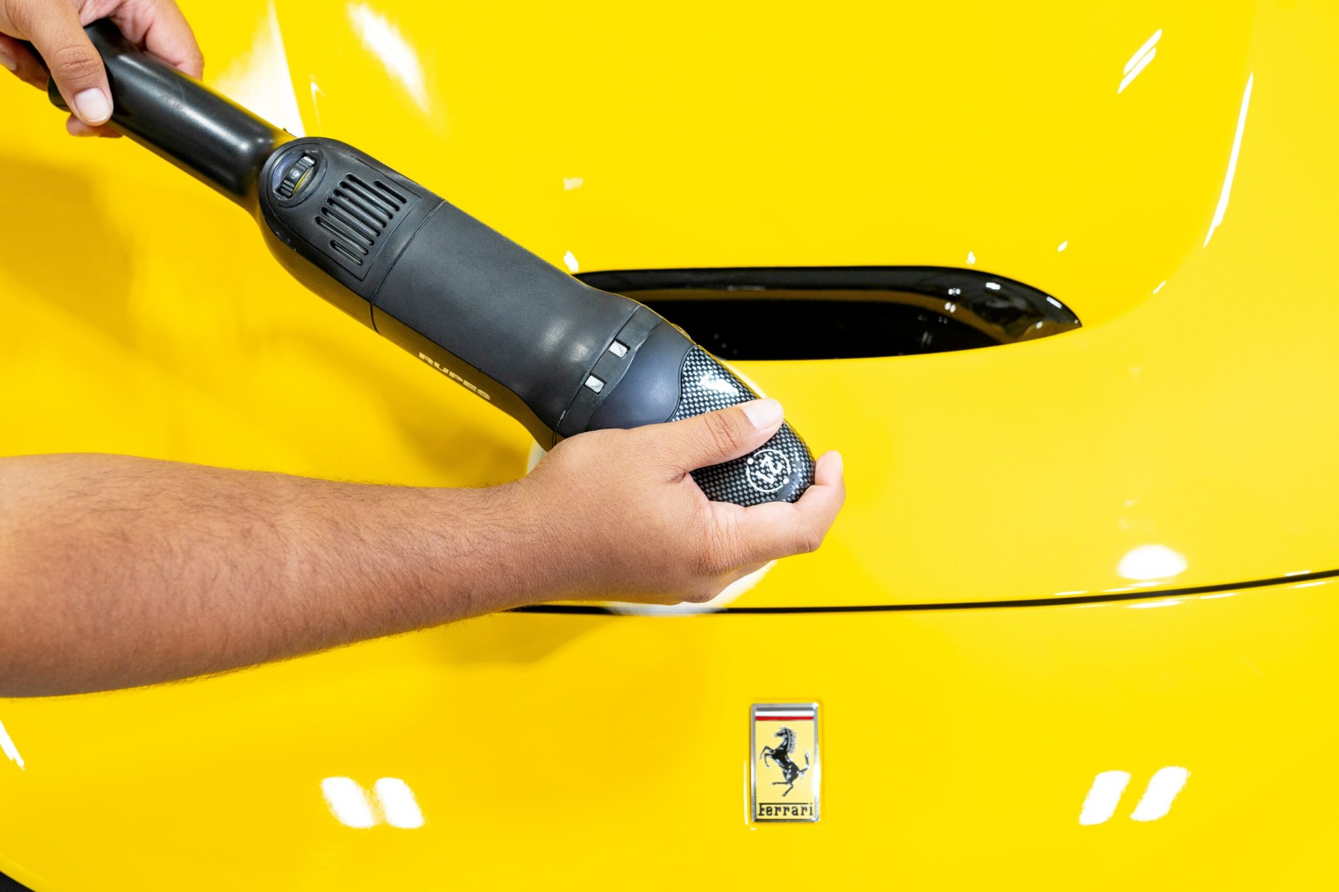 Polisher working the fender of a yellow Ferrari at ICON Auto Lab